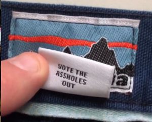 Photo of a clothing tag that reads "vote the assholes out"