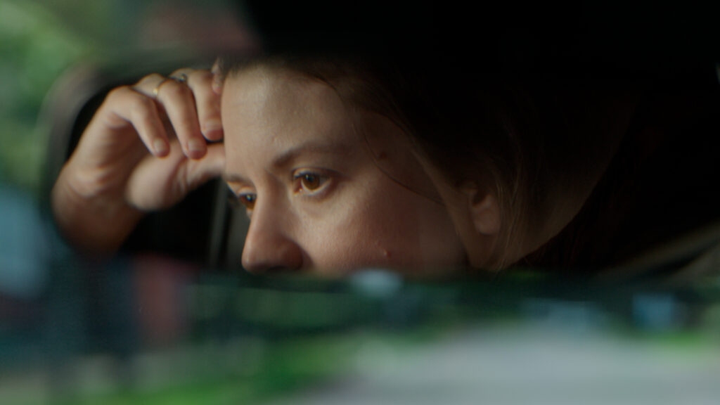 A stressed out woman is reflected in her car's rear view mirror